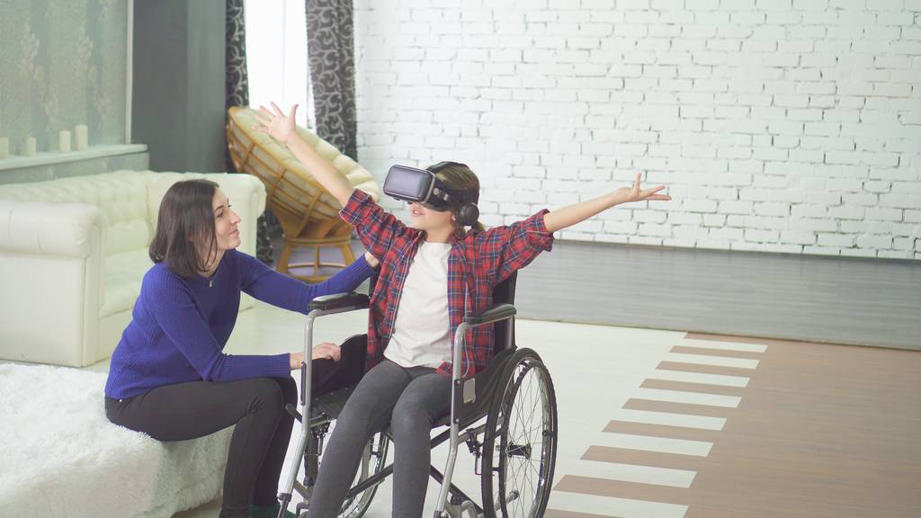 Teenage girl playing VR in a wheelchair with her mother