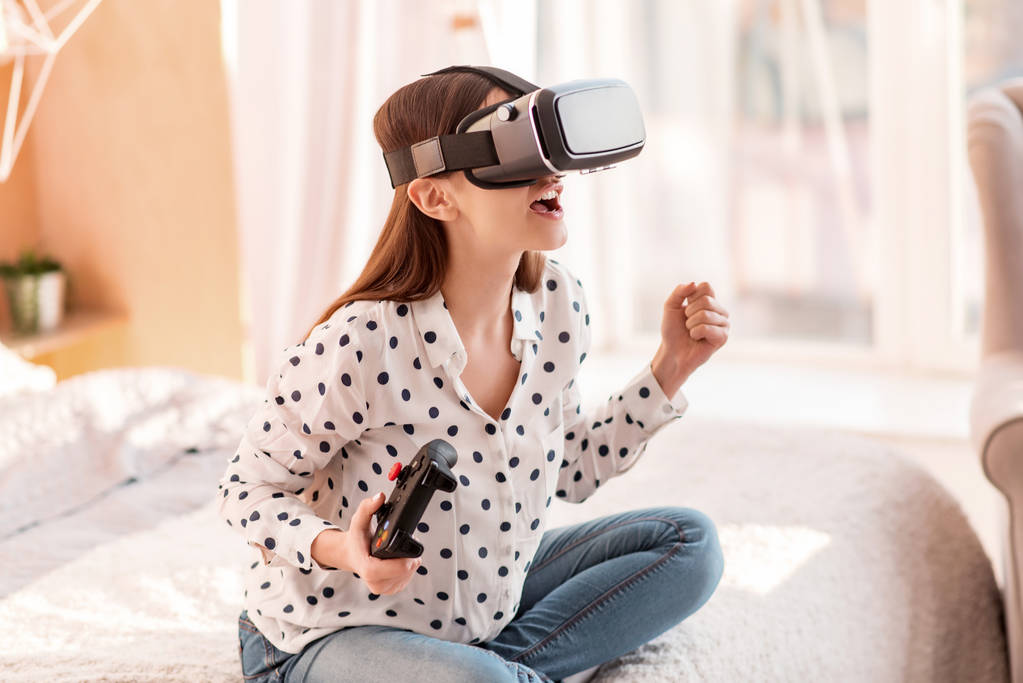 Woman playing VR in while sitting on bed