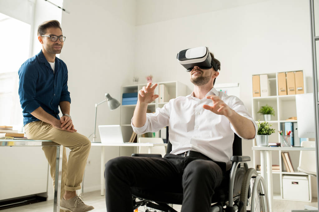 Man playing VR in a wheelchair while brother watches